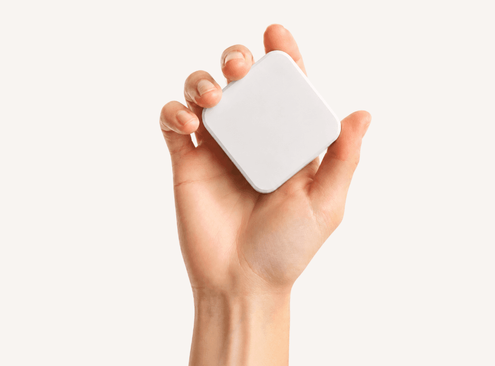 A hand holding a white Slate block against a light background