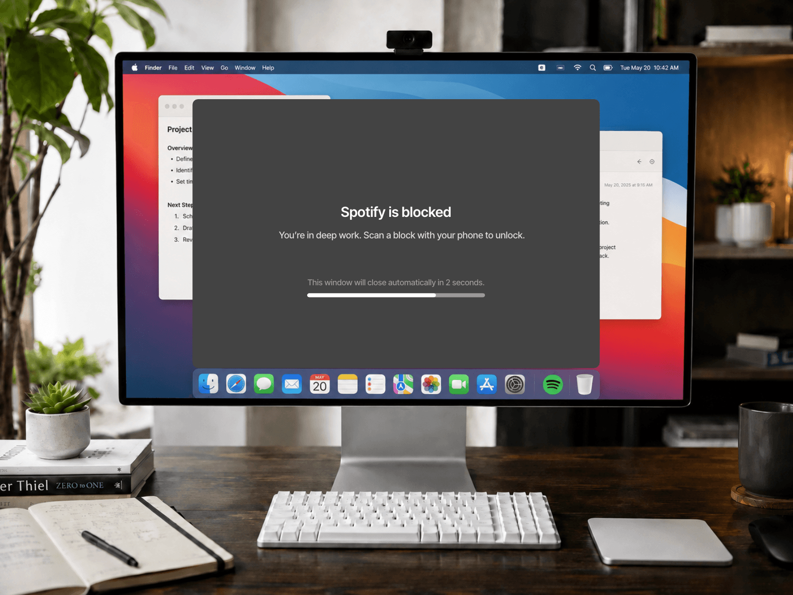 A Mac displaying a Slate block screen for Spotify beside a physical Slate Block on the desk
